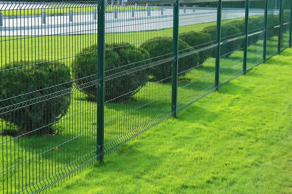 Zöld színű 3D táblás kerítés gondozott parkos környezetben